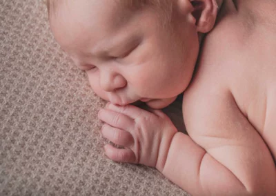 Zarte Nahaufnahme des Gesichts eines Neugeborenen mit winzigen Händen