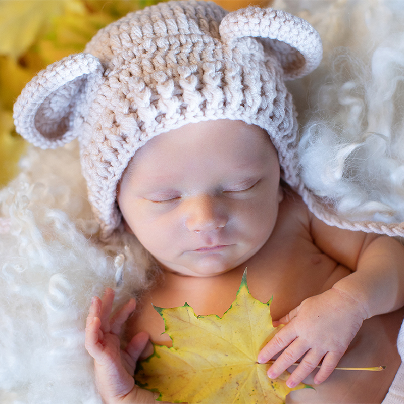 Foto von einem schlafenden Baby mit süßer Ohrenmütze und Herbstdeko